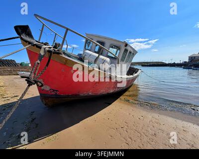 Un vieux bateau rouge échoué sur le sable du port de Youghal, comté de Cork, mer d’Irlande Banque D'Images