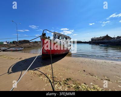 Un vieux bateau rouge échoué sur le sable du port de Youghal, comté de Cork, mer d’Irlande Banque D'Images
