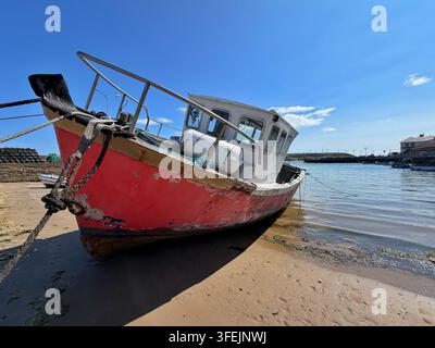 Un vieux bateau rouge échoué sur le sable du port de Youghal, comté de Cork, mer d’Irlande Banque D'Images