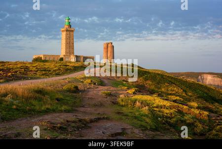 Phare du Cap Frehel au milieu des champs de bruyère en fleurs dans la lumière chaude du lever du soleil, Plevenon, Bretagne, France Banque D'Images