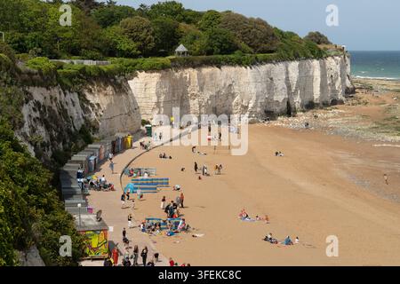 Les baigneurs se détendent et se promènent le long de Stone Bay à Broadstairs, dans le Kent, profitant d'une journée ensoleillée sous les falaises de craie blanches emblématiques. Banque D'Images