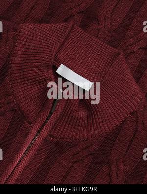 Grossissement d'un pull en tricot torsadé bordeaux avec col mock côtelé et demi-fermeture éclair. Détail vestimentaire en studio pour usage catalogue et commerce électronique. Banque D'Images