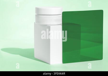 Conteneur de crème de soins minimaux sur bloc avec verre vert Banque D'Images
