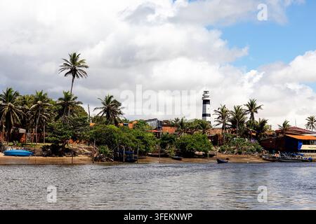 Le phare emblématique blanc et noir de Mandacaru s'élevant haut au-dessus d'un village rustique au bord de la rivière le long de la pittoresque rivière Preguicas dans le Maranhão. Banque D'Images