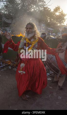 Lahore, Pakistan - 30 mars 2019 : Vue d'un dévot dansant en robes rouges et guirlandes de fleurs au festival du sanctuaire Madhu Lal Hussain, avec un tambour Banque D'Images