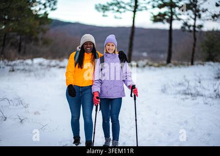 Diverses amies femmes profitant d'une randonnée hivernale sur un sentier enneigé Banque D'Images