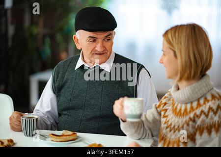Homme senior et fille adulte discutant autour d'un café Banque D'Images