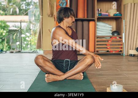 Homme faisant un exercice de yoga sur un tapis dans un studio, trouvant la paix et l'équilibre Banque D'Images