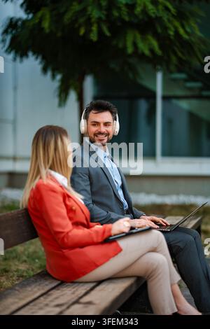 Professionnels d'affaires ayant une réunion en plein air avec ordinateur portable et casque Banque D'Images