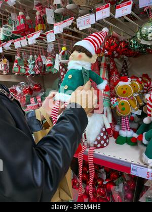 14 novembre 2024 ; Madrid, Espagne. Une personne tenant une poupée de Noël dans un magasin rempli de décorations de Noël. Boules décoratives, hommes en pain d'épice, un Banque D'Images