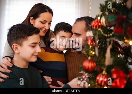 Famille décorant le sapin de Noël pour célébrer les fêtes d'hiver ensemble Banque D'Images
