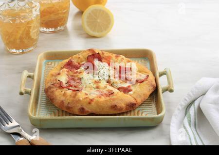Mini pizza au salami de bœuf fumé et au fromage sur une assiette carrée en céramique Banque D'Images