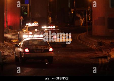 GLASGOW, UK. 4 sep 2026. Une vue dramatique en arrière capture trois voitures de patrouille fictives du département de police de Gotham naviguant sur une courbe en S prononcée de North Street. Positionnées directement sous la lourde portée en béton du pont de Kingston, les trois véhicules fonctionnent avec leurs feux d'urgence clignotants pleinement activés. La caméra se concentre précisément sur le coffre arrière du deuxième véhicule, où l'insigne « GOTHAM POLICE » est clairement visible. Crédit : Kyn Wai Chung/Alamy Live News Banque D'Images