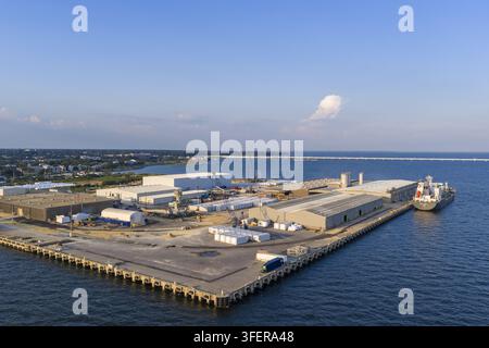 Vue aérienne du terminal d'importation de ciment CEMEX de Pensacola avec des entrepôts industriels, des installations de stockage et un navire de charge amarré au quai de Pensacola Banque D'Images