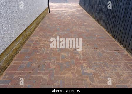 Le pavage monobloc Brindle nouvellement posé forme un motif en chevrons soigné. Le sable se dépose doucement entre chaque bord de brique. La surface fraîchement posée montre une teinte chaude, e Banque D'Images