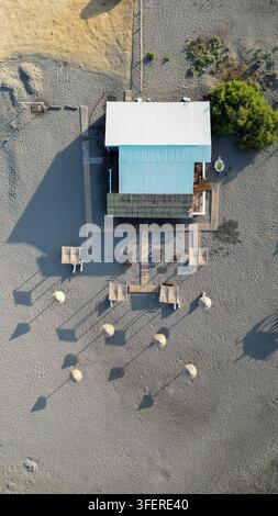 Vue aérienne du restaurant de plage Ada Bojana avec des parasols en paille et des passerelles en bois sur le sable dans la municipalité d'Ulcinj, au Monténégro. Banque D'Images