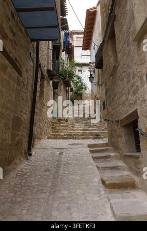 Ruelle en pierre étroite dans un village historique. Le chemin pavé mène à monter à travers les vieux bâtiments. Des balcons en bois et des plantes suspendues bordent les murs. Su Banque D'Images