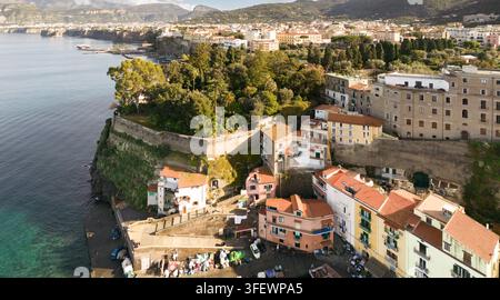 Les touristes explorent Marina Grande à Sorrente, en Italie, en admirant les maisons colorées perchées sur les falaises le long de la baie pittoresque de Naples. Banque D'Images