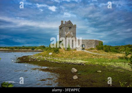 Paysage côtier du château de Dunguaire dans la baie de Kinvara, Galway, Irlande montrant le fond marin exposé par la marée basse, lors d'un après-midi d'été. Banque D'Images