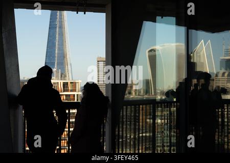 Les visiteurs en silhouette profitent de la vue sur The Shard et la skyline de Londres depuis la plateforme d'observation du Tate Modern Blavatnik Building. Banque D'Images