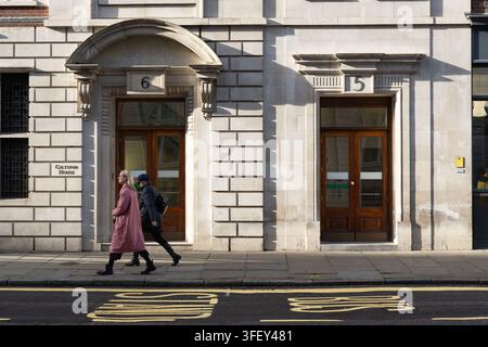 Deux femmes passent devant Giltspur House, l'ancien St Bartholomew's Medical College sur Giltspur Street, Smithfield, Londres, pendant leur trajet quotidien. Banque D'Images