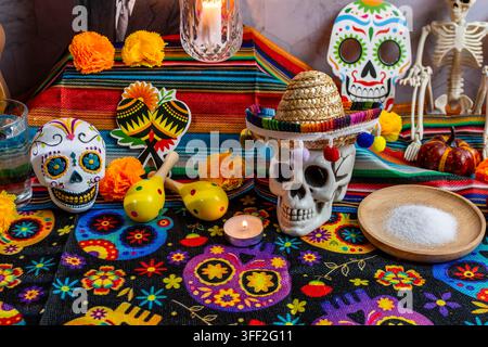 Décoration d'un autel traditionnel du Dia de Muertos avec des fleurs de souci, des crânes en sucre, des bougies et des maracas Banque D'Images
