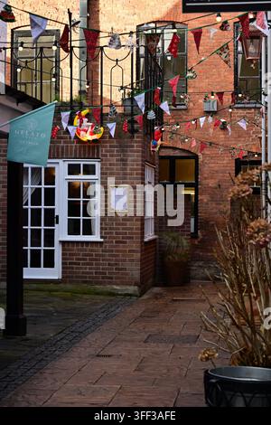 Lichfield, Royaume-Uni - 10 décembre 2025 - Ruelle festive avec guirlandes et architecture en brique de boutique de gelato Banque D'Images