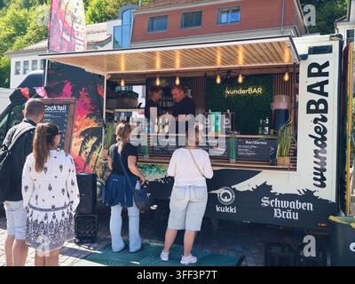 Bad Herrenalb, Allemagne, 05 septembre 2026 Les clients commandent des boissons à un bar mobile en plein air avec des lumières lumineuses, des tableaux de menus et des bouteilles, tandis que le personnel sert Banque D'Images