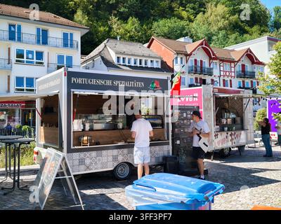Bad Herrenalb, Allemagne, 5 septembre 2026 Des stands alimentaires mobiles servent des spécialités portugaises à côté de maisons de village colorées, avec de la nourriture de rue, fiesta, po Banque D'Images