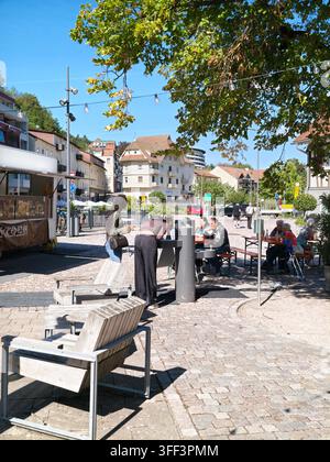 Bad Herrenalb, Allemagne, 5 septembre 2026 : place de restauration extérieure où des gens savourent des snacks de rue et des boissons sur des bancs et des tables à l’ombre des arbres Banque D'Images