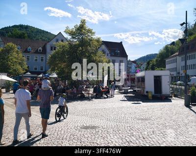 Bad Herrenalb, Allemagne, 5 septembre 2026 : Marché de rue en plein air sur une place pavée ensoleillée avec des stands de nourriture, des familles qui mangent, des cyclistes en route Banque D'Images