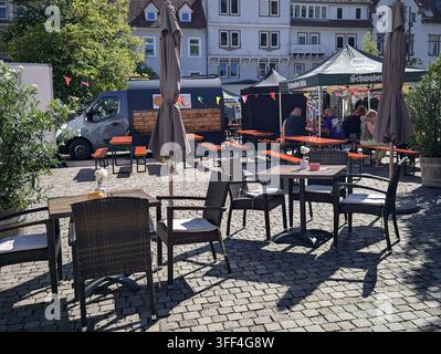 Bad Herrenalb, Allemagne, 5 septembre 2026 Scène de marché alimentaire en plein air avec des chaises en osier vides, des tables, des parasols fermés, des bancs de pique-nique, des tentes de service, Banque D'Images
