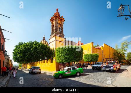 SAN MIGUEL DE ALLENDE, MEXIQUE – 1ER NOVEMBRE 2019 : Un taxi vert et un véhicule de transport municipal sont garés sur une rue pavée devant un vibran Banque D'Images