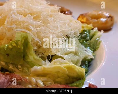 Macro rapprochée d'une salade César servie dans une assiette blanche. Les feuilles de laitue romaine fraîches sont recouvertes d'une sauce César crémeuse et garnies d'un Banque D'Images
