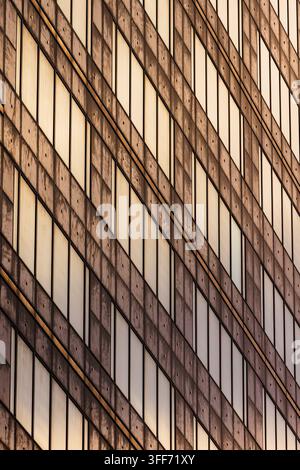 Une façade de bâtiment présentant un motif répétitif en grille de fenêtres rectangulaires verticales et de poutres structurelles en béton. Banque D'Images