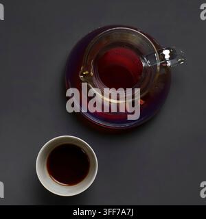 Vue aérienne d'un café noir chaud dans une carafe en verre et une tasse en céramique sur un fond sombre Banque D'Images