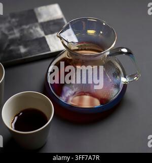 Café chaud fraîchement infusé dans une carafe en verre et une tasse blanche sur une surface sombre Banque D'Images