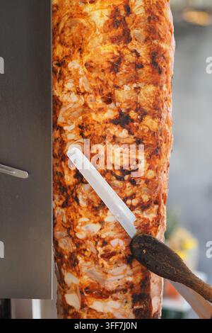 Shawarma Doner Kebab sur rotisserie verticale étant tranché pour des wraps et sandwichs de street food Banque D'Images