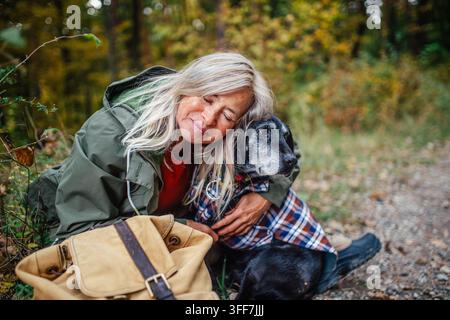 Propriétaire de chien aimante câlinant son animal de compagnie pendant une promenade paisible en automne. Banque D'Images