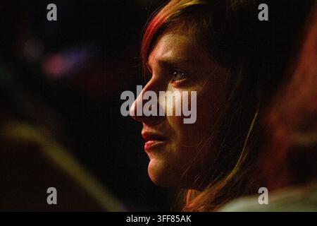 VISAGE DE JEUNE FEMME DE PROFIL À UN CONCERT, REPORTAGE, FESTIVAL GREEN MAN 2013, BRECON, PAYS DE GALLES, ROYAUME-UNI, 2013 : Un portrait candide en gros plan capture le profil d'une jeune femme aux cheveux roux, son visage illuminé par une lumière chaude alors qu'elle observe intensément quelque chose dans l'obscurité. Photo : Rob Watkins. INFO : Le Festival Green Man se tient chaque année dans les Brecon Beacons en août. Il célèbre la musique alternative, les arts, la littérature, la science et une culture familiale dans un magnifique cadre montagneux. L'événement de 2013 marquait la 10e édition anniversaire. Banque D'Images