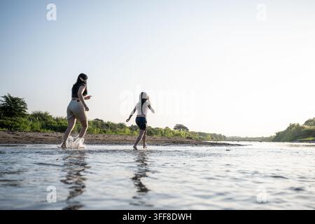 Mère et fille marchant le long d'une rivière à l'heure dorée Banque D'Images