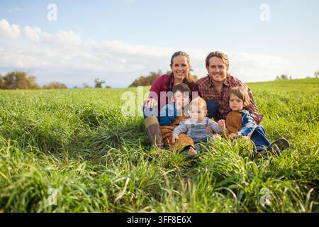 Famille heureuse de cinq personnes posant dans un champ vert Banque D'Images