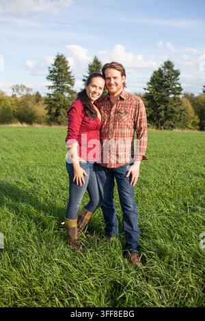 Couple heureux debout ensemble dans un champ herbeux Banque D'Images