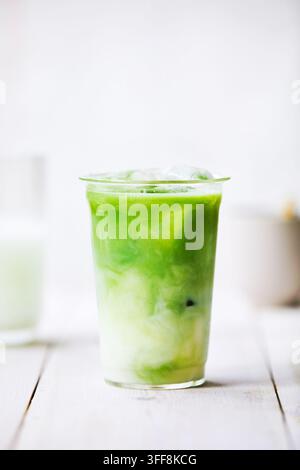 Latte matcha dans un verre. Matcha et lait se mélangent. Atmosphère de cuisine lumineuse, fraîche et conviviale. Banque D'Images