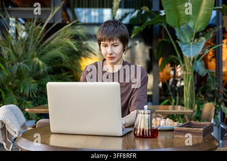 Femme aux cheveux courts travaillant dans un café et semblant absorbée Banque D'Images