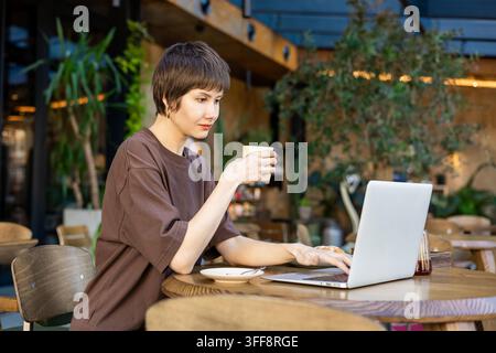 Femme aux cheveux courts travaillant dans un café et semblant absorbée Banque D'Images