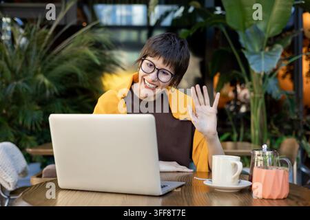Femme aux cheveux courts et lunettes ayant un appel vidéo et paraissant concentrée Banque D'Images