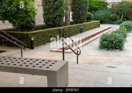 Banc en pierre moderne et escaliers en béton surplombant un jardin paysager Banque D'Images