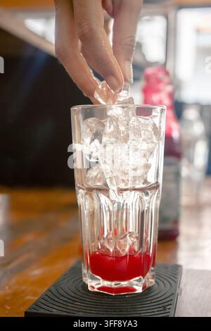 Sélection de boissons servies dans un café-bar, comprenant un verre de bière ambrée, un latte au matcha, un thé glacé et un verre en cours de préparation avec des glaçons. Banque D'Images