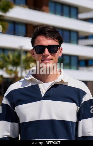 Jeune homme portant des lunettes de soleil dans une marina Banque D'Images